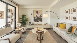 A modern living room with a sofa, a dining table, and a bookshelf.