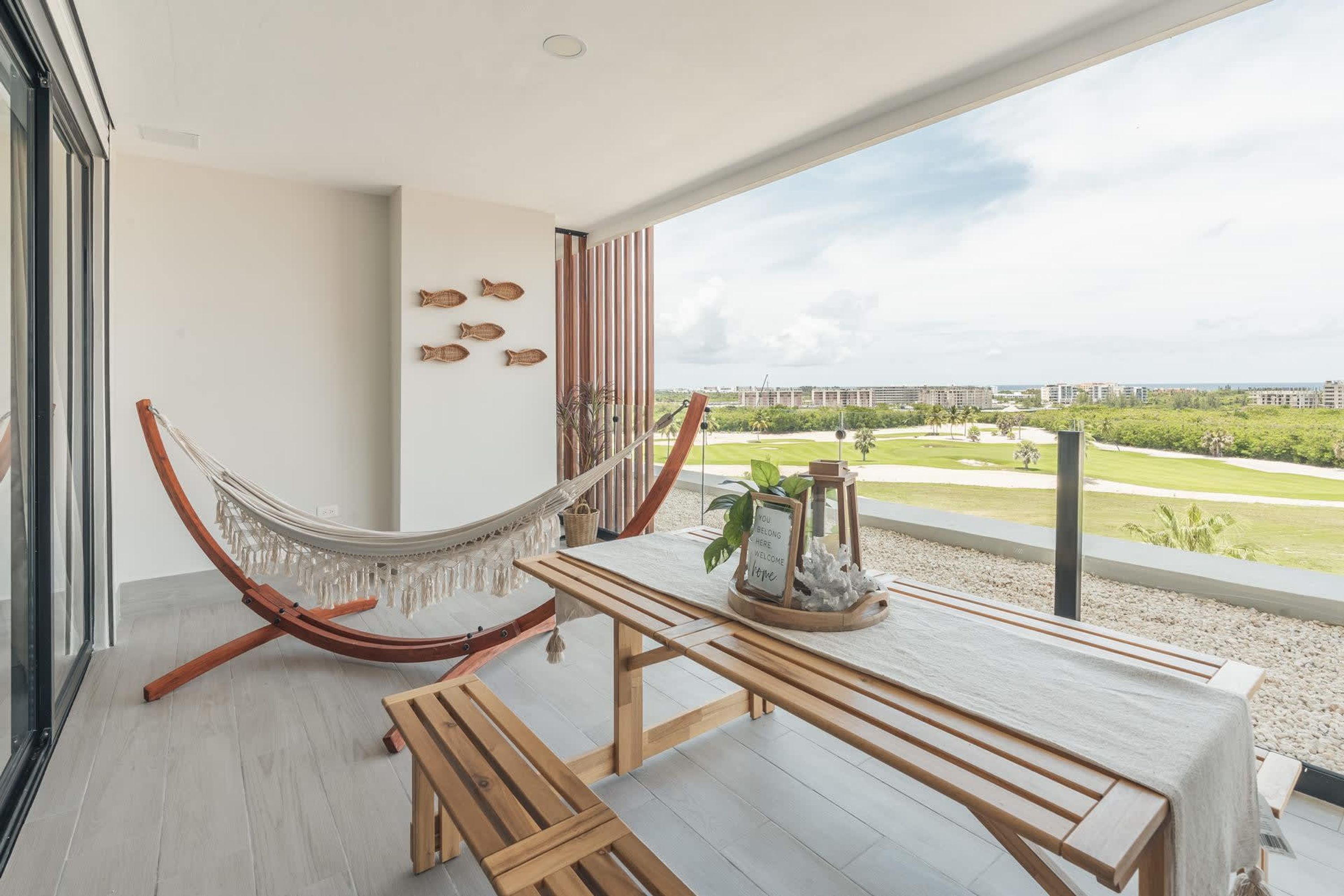 Ein Balkon mit einer Hängematte, einem Holztisch und Blick auf eine Stadtansicht.