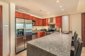 A modern kitchen with granite countertops, stainless steel appliances, and wooden cabinets. - Apartment With Ocen View at Punta Palmera Cb4 (Punta Cana)