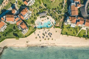 An aerial view of a resort with a central swimming pool, beachfront, and multiple buildings with red-tiled roofs. - Apartment With Ocen View at Punta Palmera Cb4 (Punta Cana)