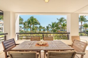 A wooden table with chairs, a decorative centerpiece, and a view of palm trees and a pool. - Apartment With Ocen View at Punta Palmera Cb4 (Punta Cana)