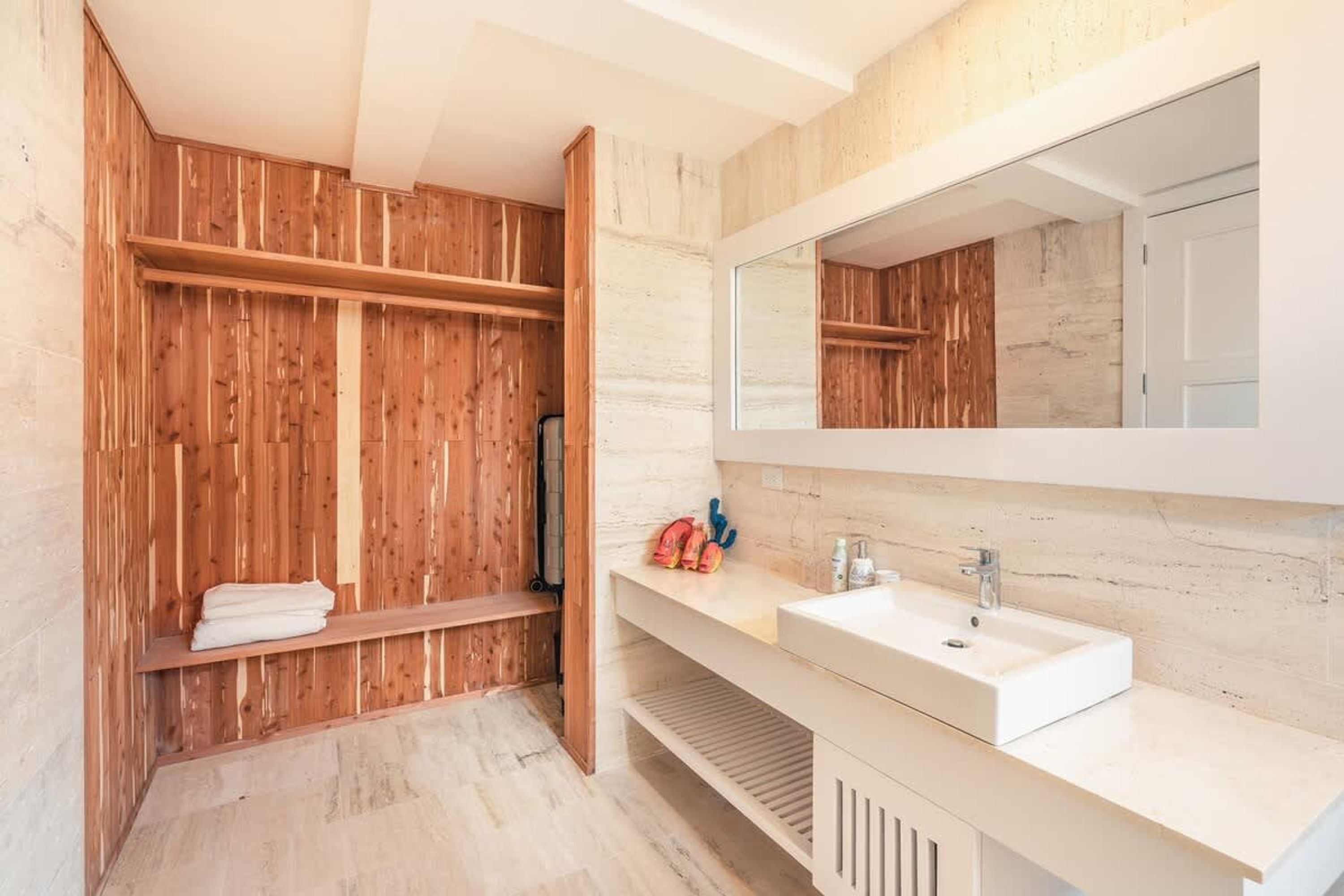 A modern bathroom with a wooden vanity, a large mirror, and a built-in shelf.