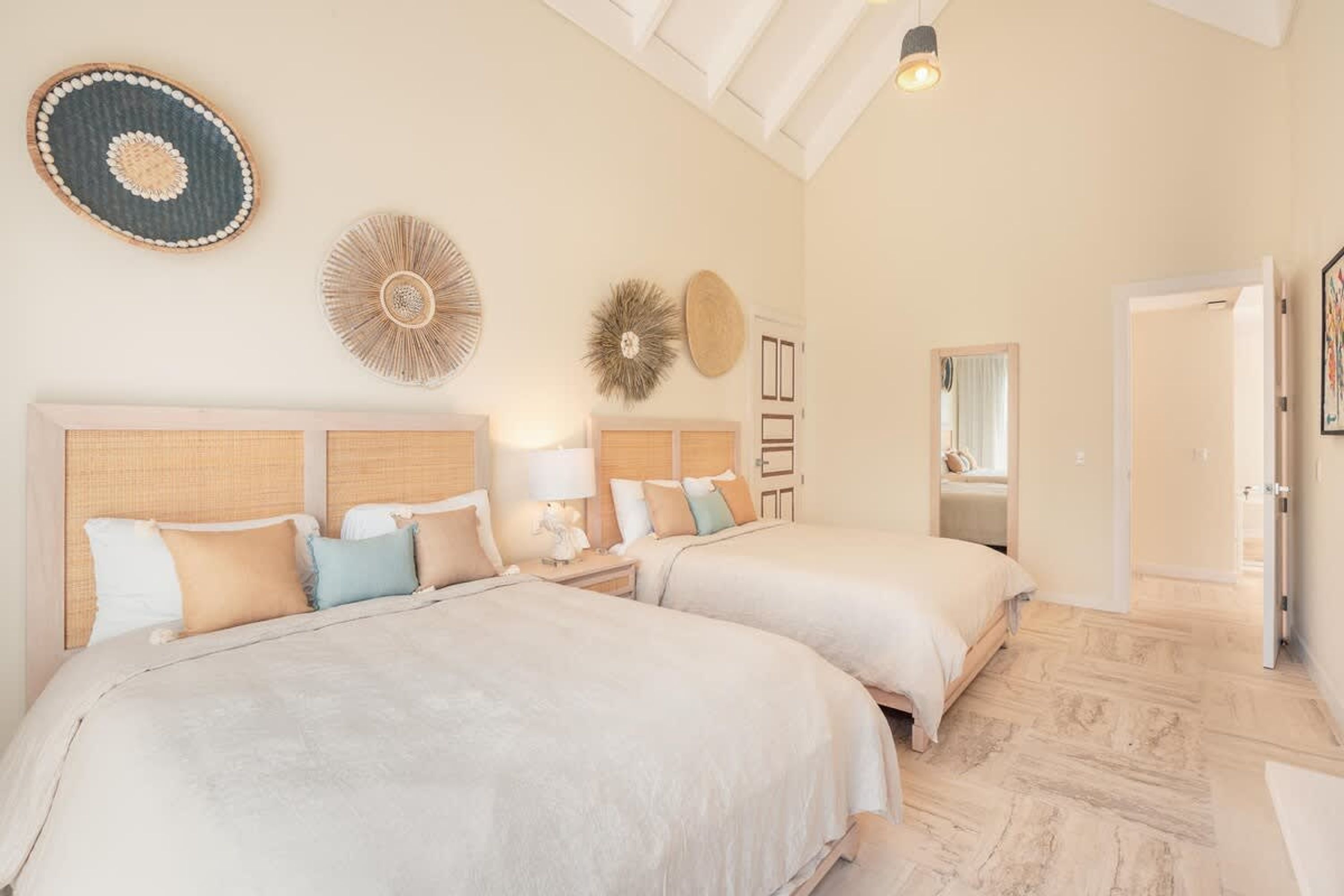 A hotel room with two beds, a large mirror, and a ceiling fan.