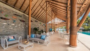 A covered outdoor lounge area with stone walls, bamboo columns, and a pool. - 2 Br 6 Guests Nearby Beach Portillo (Las Terrenas)