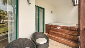 A balcony with wicker chairs, a wooden staircase, and a hot tub. - 2br Apt 5 Guests Balcony With Pool View (Las Terrenas)