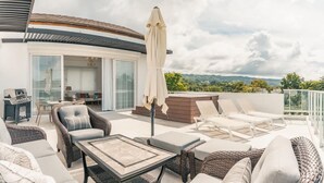 A rooftop terrace with wicker furniture, a table, and an umbrella. - 3br-penthouse w Jacuzzi Incl at Lake View (Las Terrenas)