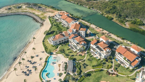 An aerial view of a resort with multiple buildings, a swimming pool, and a beach. - Apartment few Steps to the Beach at Punta Palmera (Punta Cana)