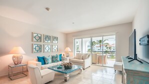 A modern living room with a sofa, armchairs, a coffee table, and a TV. - Apartment few Steps to the Beach at Punta Palmera (Punta Cana)