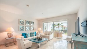 A modern living room with a sofa, armchairs, a coffee table, and a TV. - Apartment few Steps to the Beach at Punta Palmera (Punta Cana)