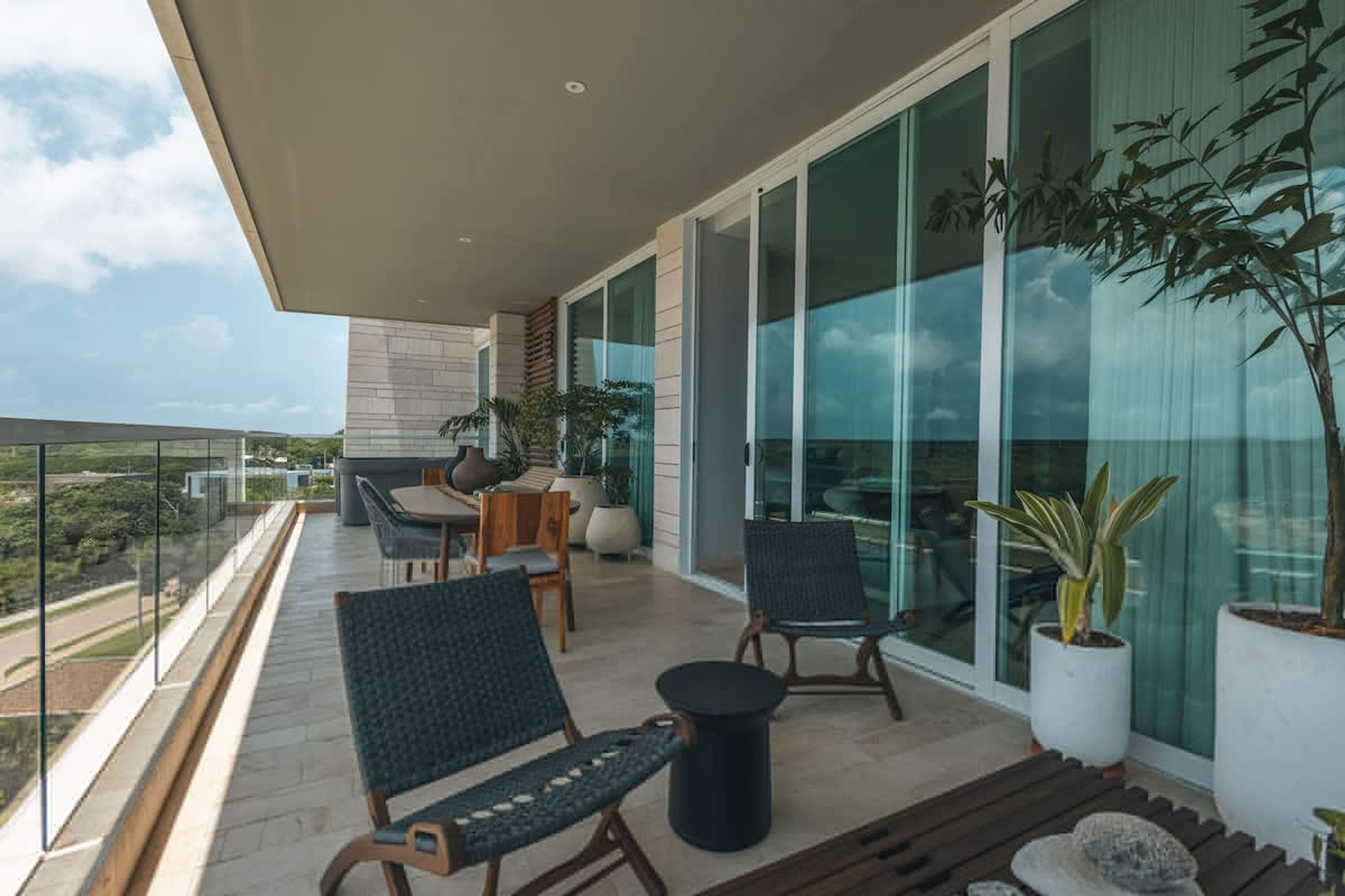 Ein Balkon mit Sitzgelegenheit, einem Tisch und Blumentöpfen.