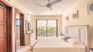 Ein Schlafzimmer mit einem Bett, einem Deckenventilator, einem großen Fenster und einem Balkon.