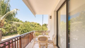 Ein Balkon mit Tisch und Stühlen, einem Geländer und Blick auf Grünflächen und ein Gebäude.