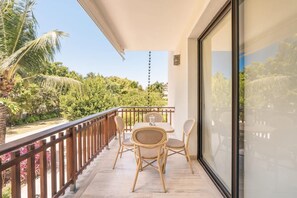 Ein Balkon mit Tisch und Stühlen, einem Geländer und Blick auf Grünflächen und ein Gebäude.