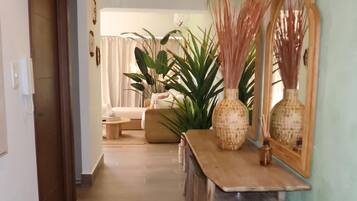 A hallway with a patterned carpet, wooden console table, wicker vases, and a mirror.