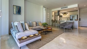 A modern living room with a sofa, coffee table, and a dining area with chairs. - 3br-apt 6 Guests Jacuzzi Calablanca (Cartagena)