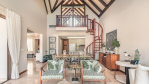Un vaste salon doté d’un haut plafond, un coin repas et un escalier menant à l’étage supérieur.