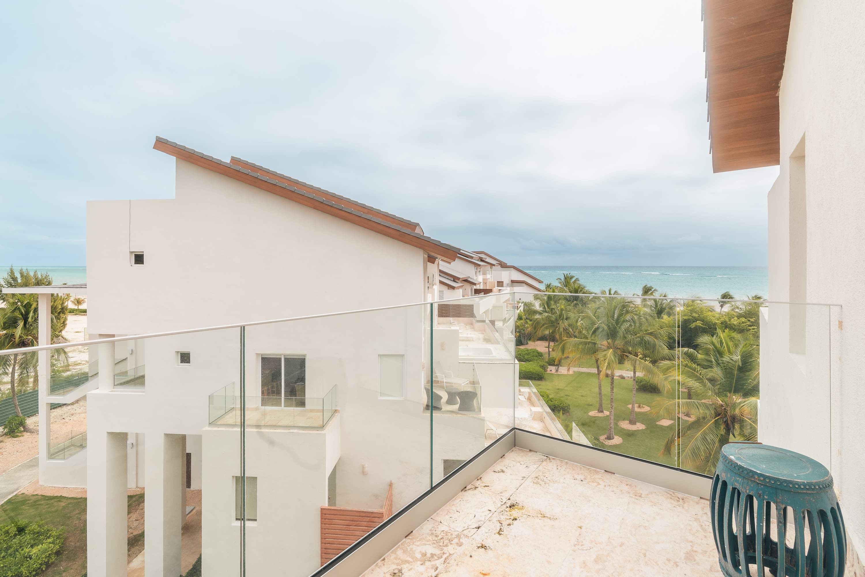 Ein modernes Gebäude mit einem Balkon mit Blick auf Strand und Palmen.