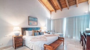 Una camera da letto con un letto, comodini, una panca, una lampada e un quadro appeso al muro.
