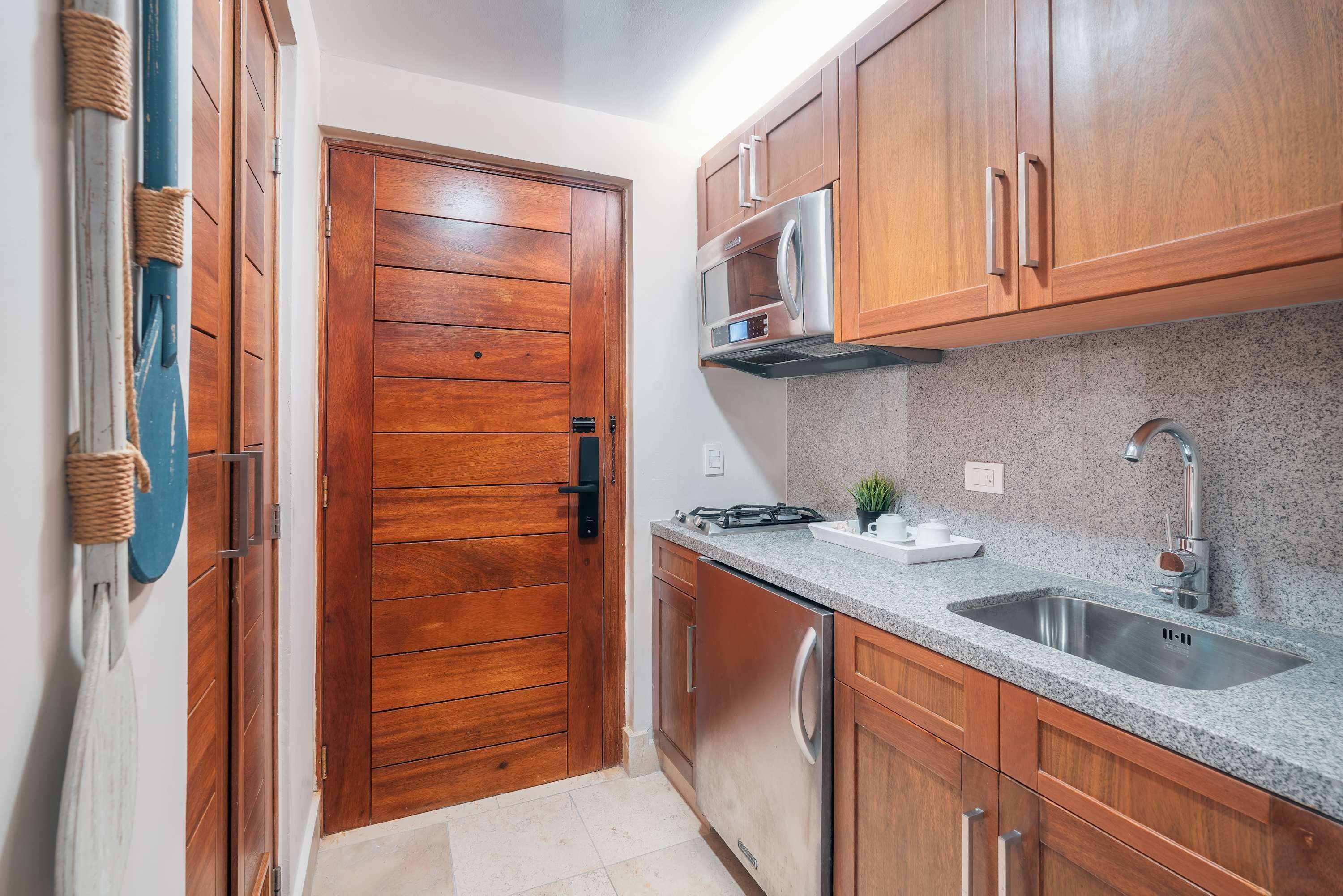 A kitchen with wooden cabinets, a stainless steel sink, and a microwave.