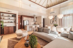 A modern living room with a sofa, coffee table, and a dining area with chairs. - Incredible 3br Bungallow With Patio and Pool (Punta Cana)