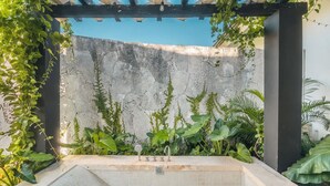 Un área de spa con pared de piedra, suelo de baldosas y una estructura de pérgola.