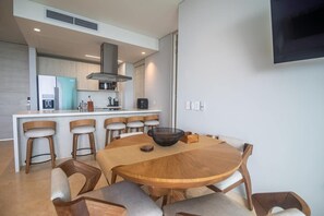 A modern kitchen with a central island, bar stools, and a round dining table.