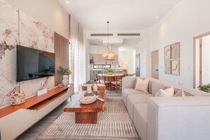 A modern living room with a flat-screen TV, wooden coffee table, and a sofa. - New Loft With 2br and Golf View in Cap Cana (Punta Cana)