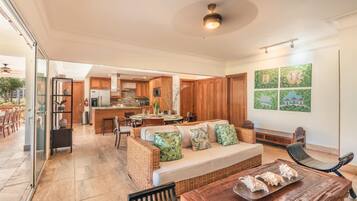 A spacious living area with a sofa, a dining table, and a kitchen in the background.
