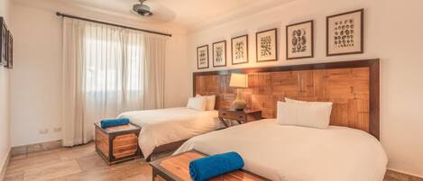 A hotel room with two beds, a wooden headboard, a nightstand, and a window with curtains.