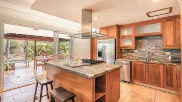 A modern kitchen with a central island, wooden cabinets, and a stone backsplash.