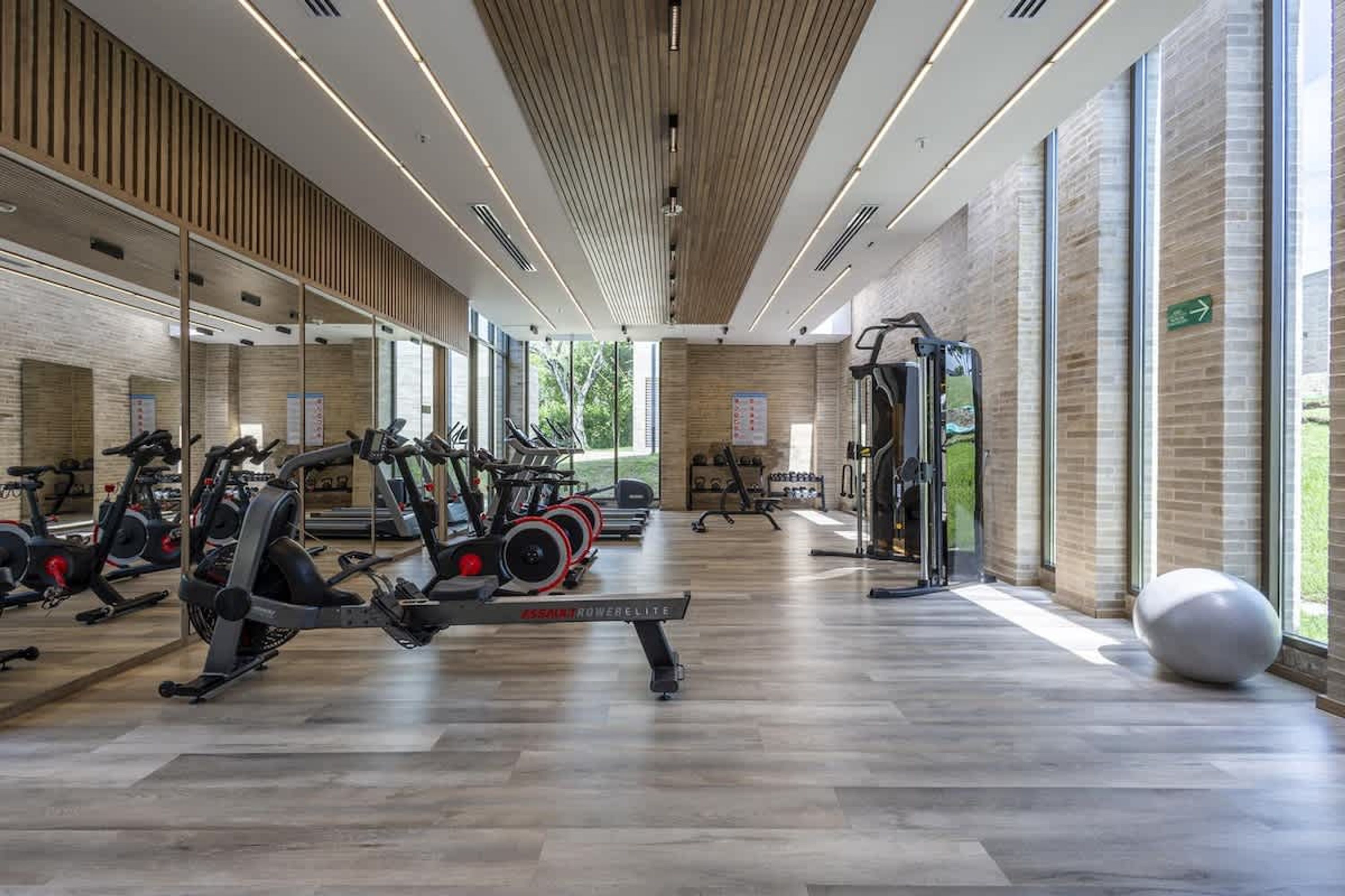 A gym with cardio machines, free weights, and a mirrored wall.