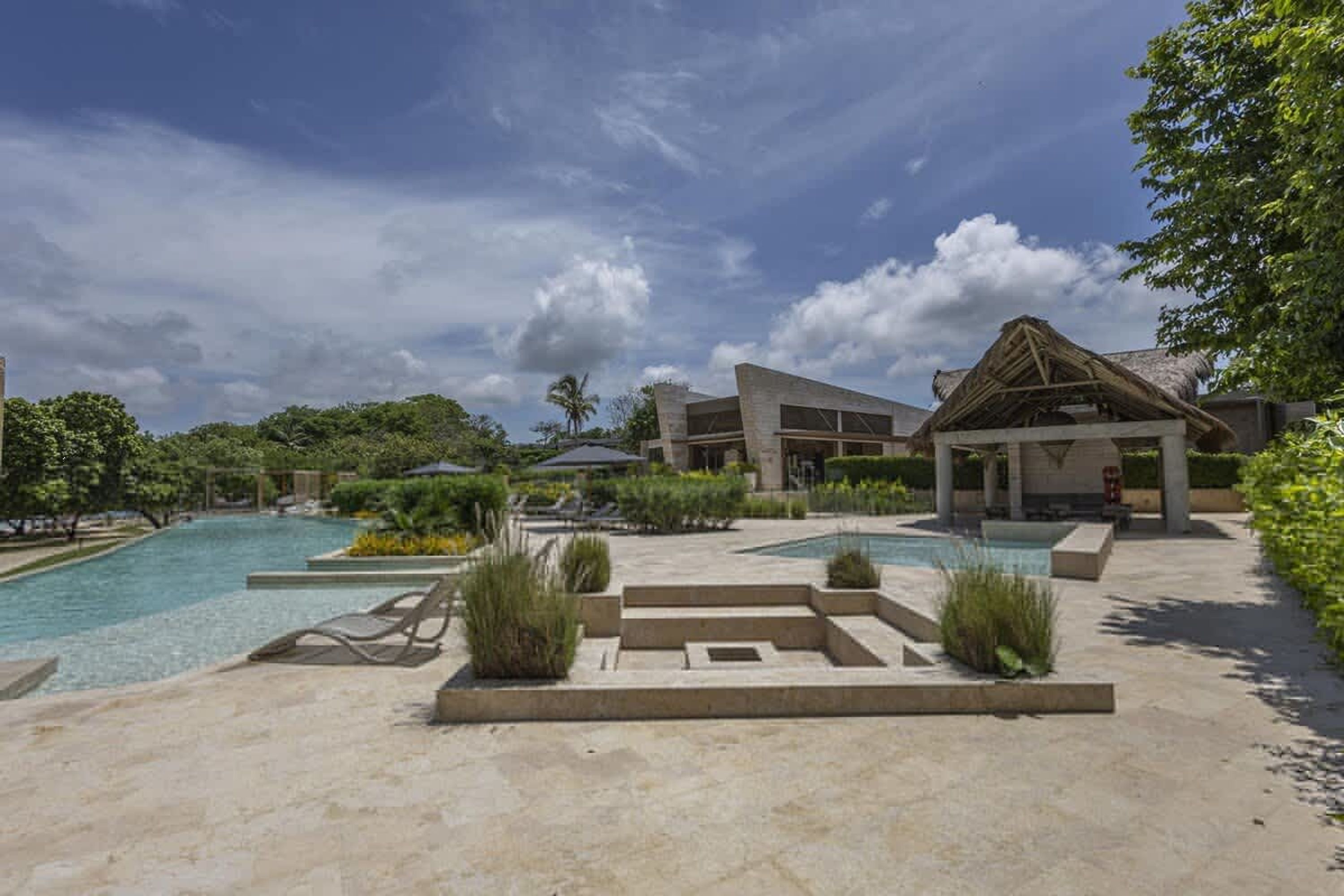 Un resort con piscina, sillas de descanso y un pabellón.