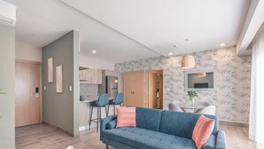 A modern living room with a sofa, a dining area with chairs, a kitchen in the background, and a patterned wall. - Regatta Living Ii - 705 (Santo Domingo)