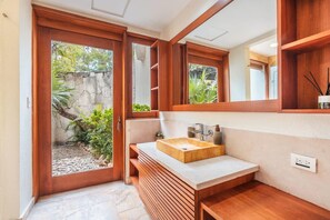 A bathroom with a wooden vanity, a large mirror, and a view of the garden. - Amazing Villa w Pool Maid BBQ at Green Village (Punta Cana)