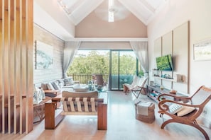 A spacious living area with a sofa, chairs, a coffee table, and a TV.
