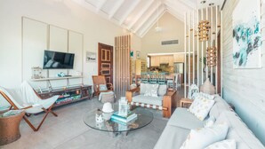 A spacious living area with a television, seating, and a kitchen in the background. - Retreat Apartment With 3 Bedrooms in Portillo Nf (Las Terrenas)