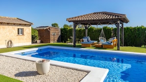 A swimming pool with a pergola and outdoor seating, surrounded by a well-maintained lawn and a small building. - Sunnyvalley by Fidalsa (Dolores)
