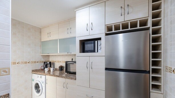 A modern kitchen with stainless steel appliances, a washing machine, and light-colored cabinets. - Fidalsa Bay View Romance (Guardamar del Segura)