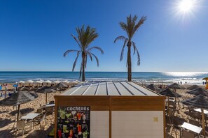 A beachside bar with a menu board, palm trees, and beach umbrellas. - Fidalsa Bay View Romance (Guardamar del Segura)