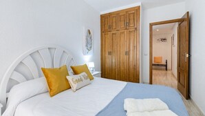 A bedroom with a bed, wooden wardrobe, and a nightstand. - Fidalsa Bay View Romance (Guardamar del Segura)