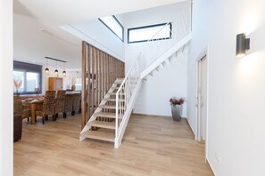 Un intérieur moderne avec un escalier en bois, un coin repas et une cuisine.