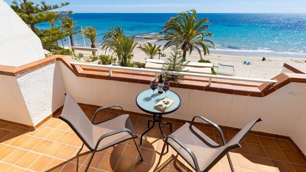 A balcony with a table and chairs, overlooking a beach with palm trees and the sea. - Fidalsa Famous Spot by Fidalsa (Orihuela)