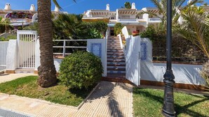 A residential building with a staircase leading to a gated entrance, surrounded by palm trees and a well-maintained lawn. - Fidalsa Famous Spot by Fidalsa (Orihuela)