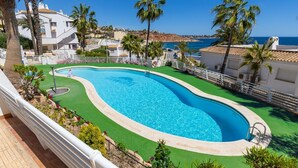 A swimming pool with a curved edge, surrounded by a white fence and palm trees. - Fidalsa Famous Spot by Fidalsa (Orihuela)