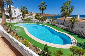 Una piscina de vora corbada, envoltada per una tanca blanca i palmeres.