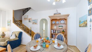 A dining area with a round table set for breakfast, a staircase, and a bookshelf with decorative items. - Fidalsa Famous Spot by Fidalsa (Orihuela)
