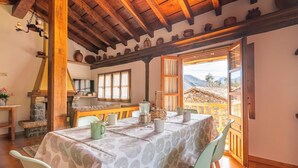 A dining area with a table set for four, wooden beams on the ceiling, stone steps, and a view of a mountainous landscape through an open door. - Fidalsa Paradise Point (Cabezon de Liebana)