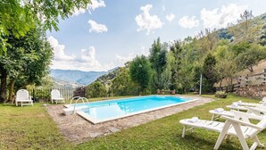 A swimming pool with lounge chairs and a stone pathway. - Fidalsa Paradise Point (Cabezon de Liebana)