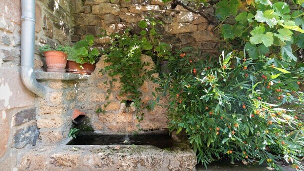 A stone wall with a small water feature and potted plants. - Fidalsa Paradise Point (Cabezon de Liebana)