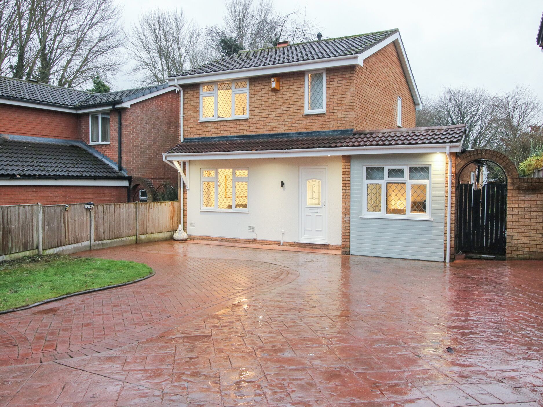 A two-story house with a brick exterior, a garage, and a paved driveway.